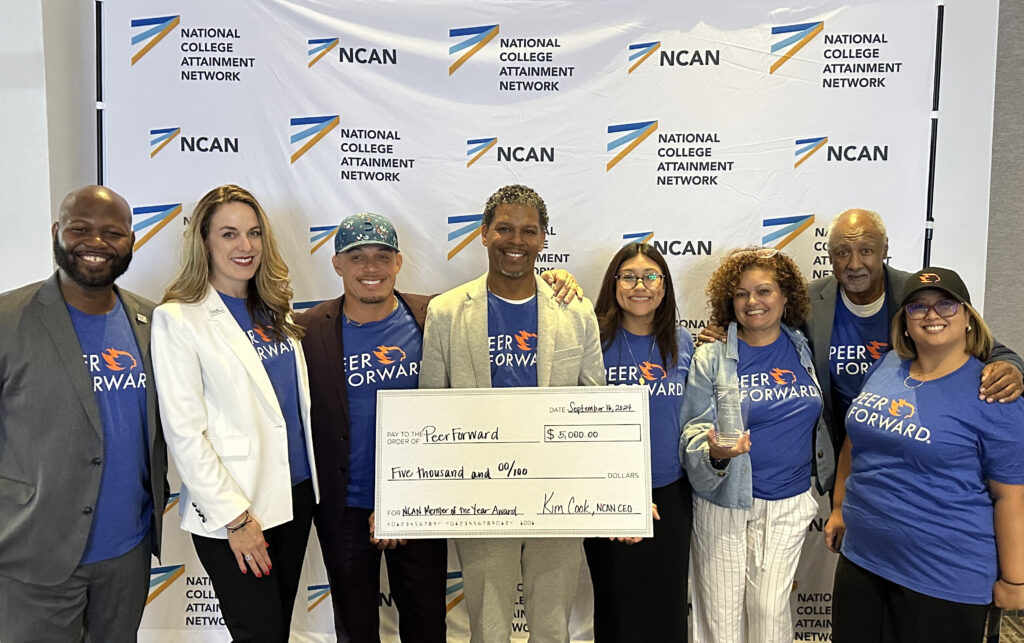 PeerForward staff poses with large check in front of National College Attainment Network backdrop. 